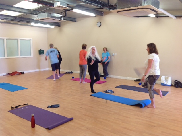 Pink, purple, green and blue mats laid out as people set up and chat before class