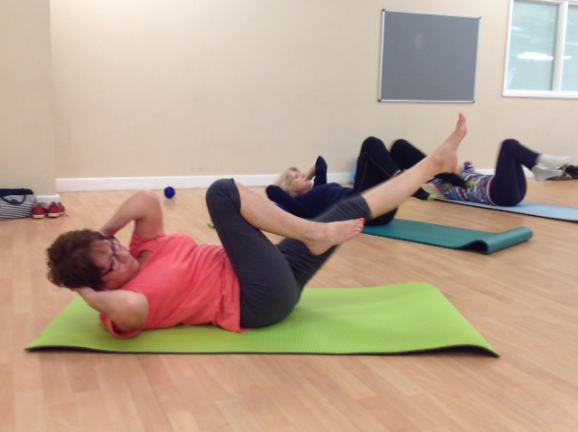 Two people on green and purple mats doing a lying twist